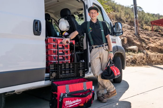 Pro with work van door open posing with tool boxes