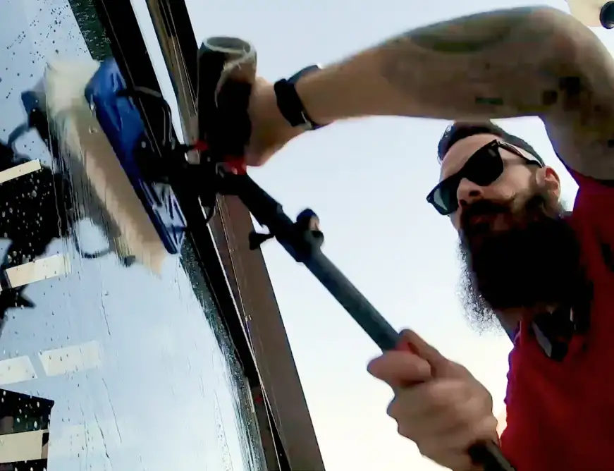 Male pro with bead and sunglasses cleaning window 